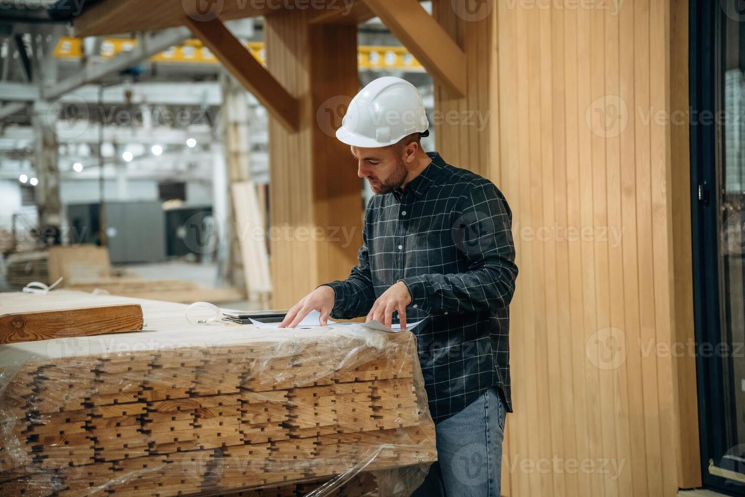 In,, white helmet. Male builder is at construction of wooden house photo