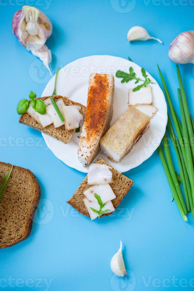 Black bread with lard and onions - top view, isolated on a blue background photo