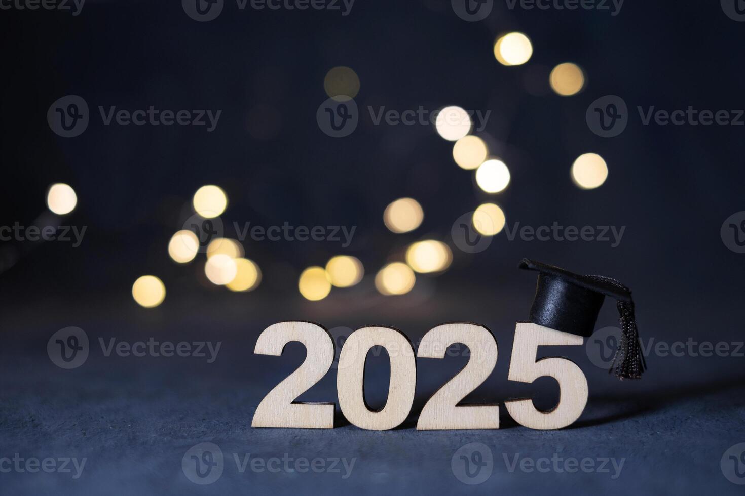 Wooden number 2025 with graduated cap on dark background with bokeh. Class of 2025 concept photo
