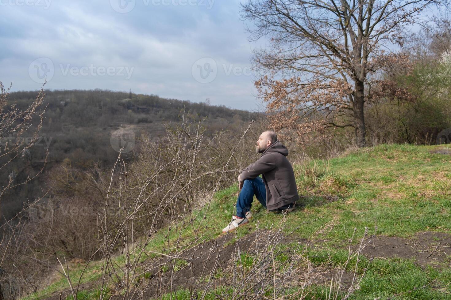 Individual enjoys tranquil moment overlooking expansive hillside landscape in early springtime weather photo