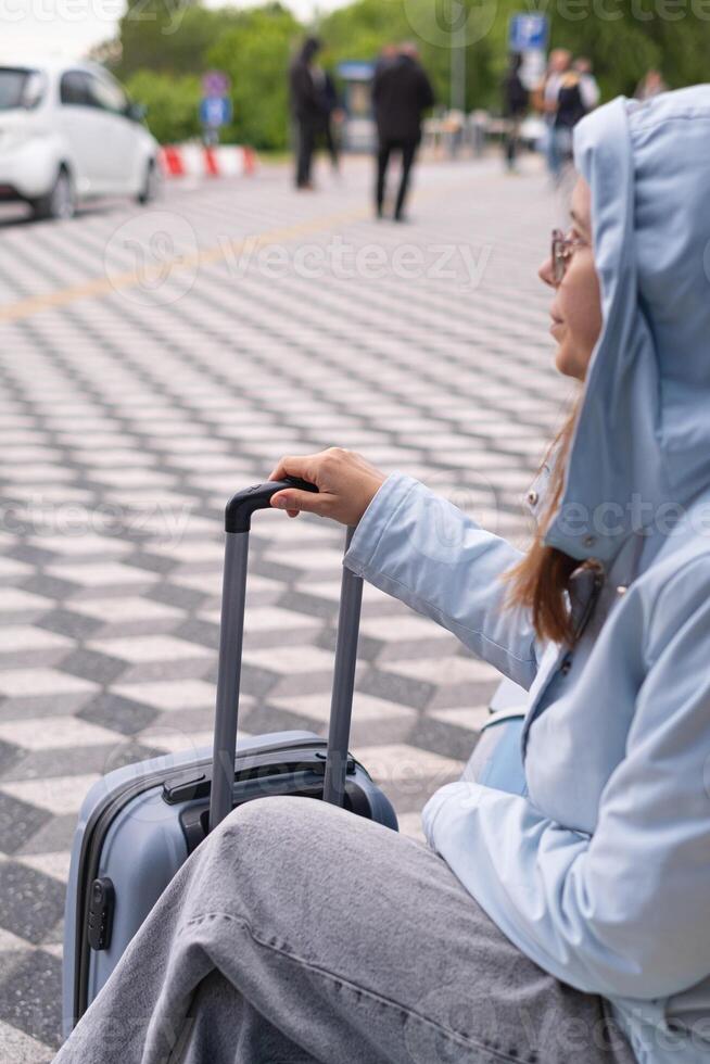 Waiting at the airport with a suitcase on a patterned walkway photo