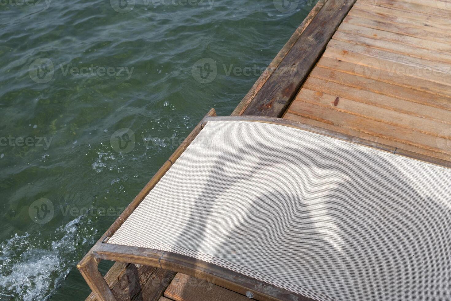 Shadow heart formed by hands on a sun lounger by the sea during a sunny day photo