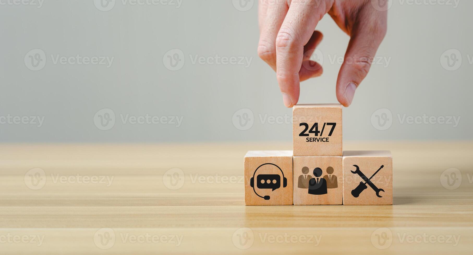 Hand placing a wooden block with 24 7 Service text on top of other blocks featuring icons of customer support, teamwork, and technical service, representing continuous business support photo