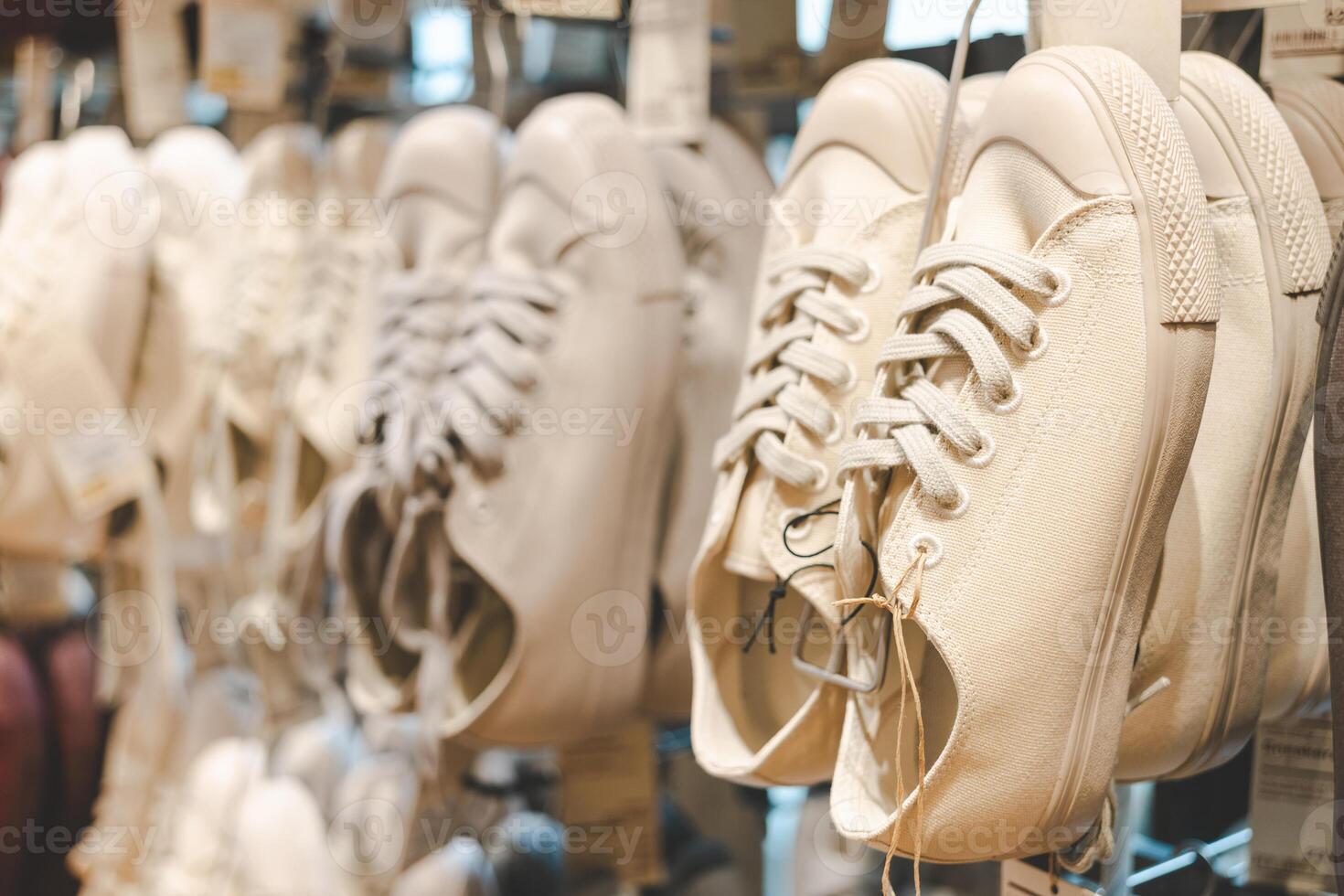 Classic Canvas Sneakers on Display in a Fashion Retail Store. Several pairs of canvas sneakers hanging neatly on display in a modern fashion retail store. Ideal for themes related to fashion. photo