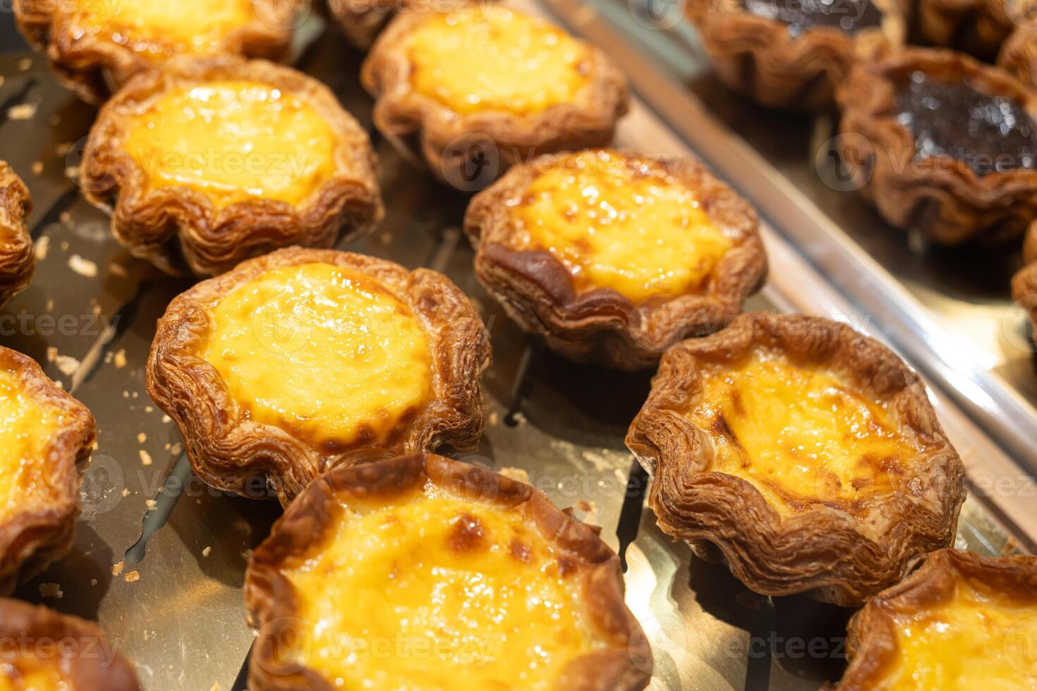 Freshly Baked Portuguese Egg Tarts on Display Tray. Crispy Crust and Creamy Custard Filling. Close up of delicious Portuguese egg tarts freshly baked and arranged on a display tray. photo
