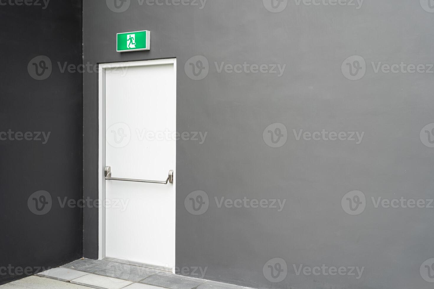 Emergency Exit Door with Green Sign on Grey Wall for Safety and Evacuation Concept. Copy space photo
