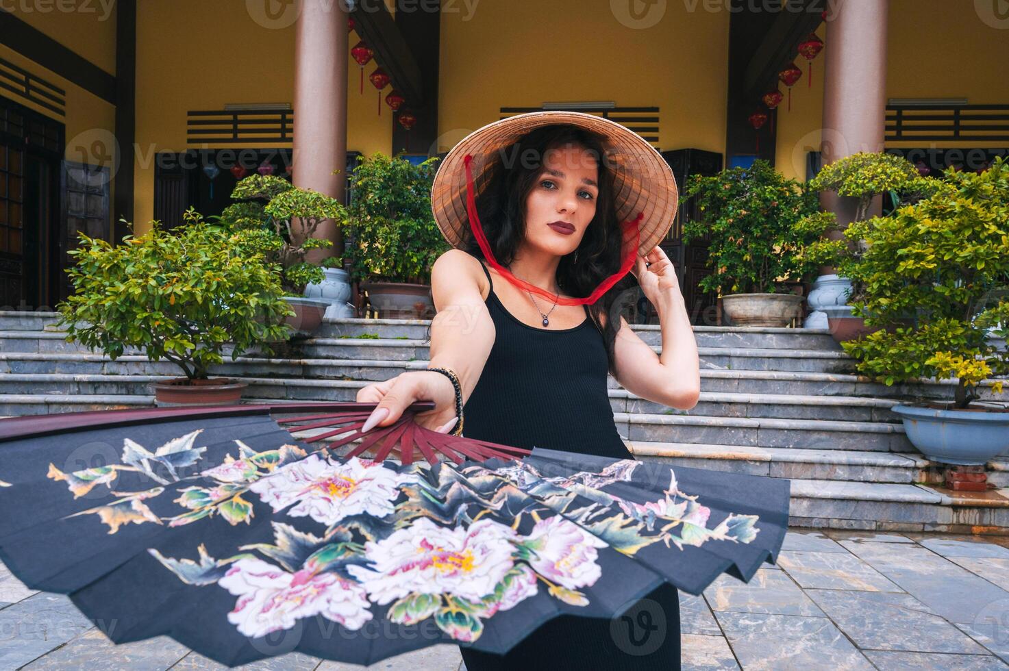 A tourist woman in a Vietnamese Non La hat and a painted fan on the background of beautiful landscapes at Linh Ung pagoda in Da Nang. photo