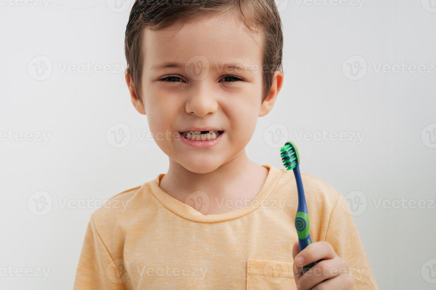 Portrait of a smiling little boy without a baby tooth with a toothbrush, close-up. Oral care in children. photo