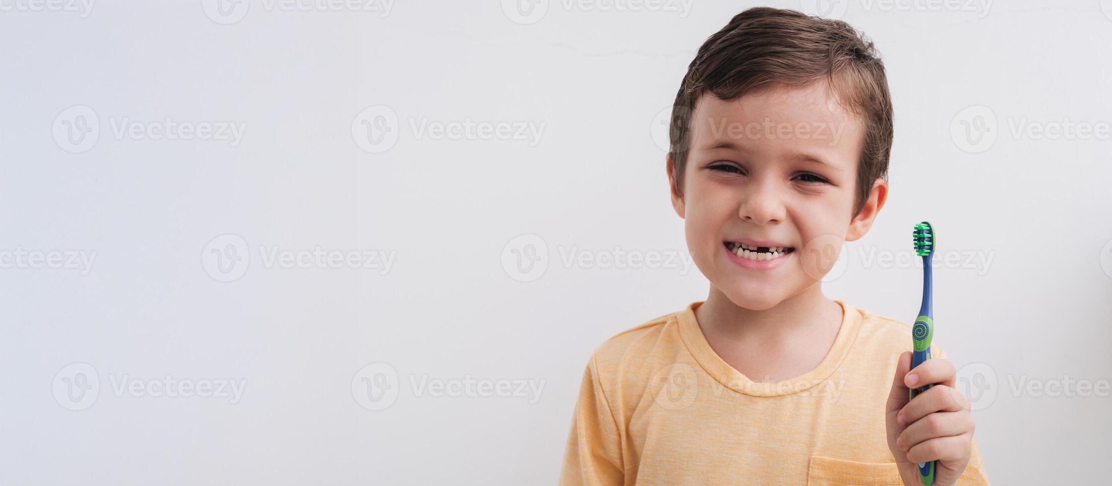 Portrait of a smiling little boy without a baby tooth with a toothbrush, close-up. Panoramic banner. Oral care in children. photo