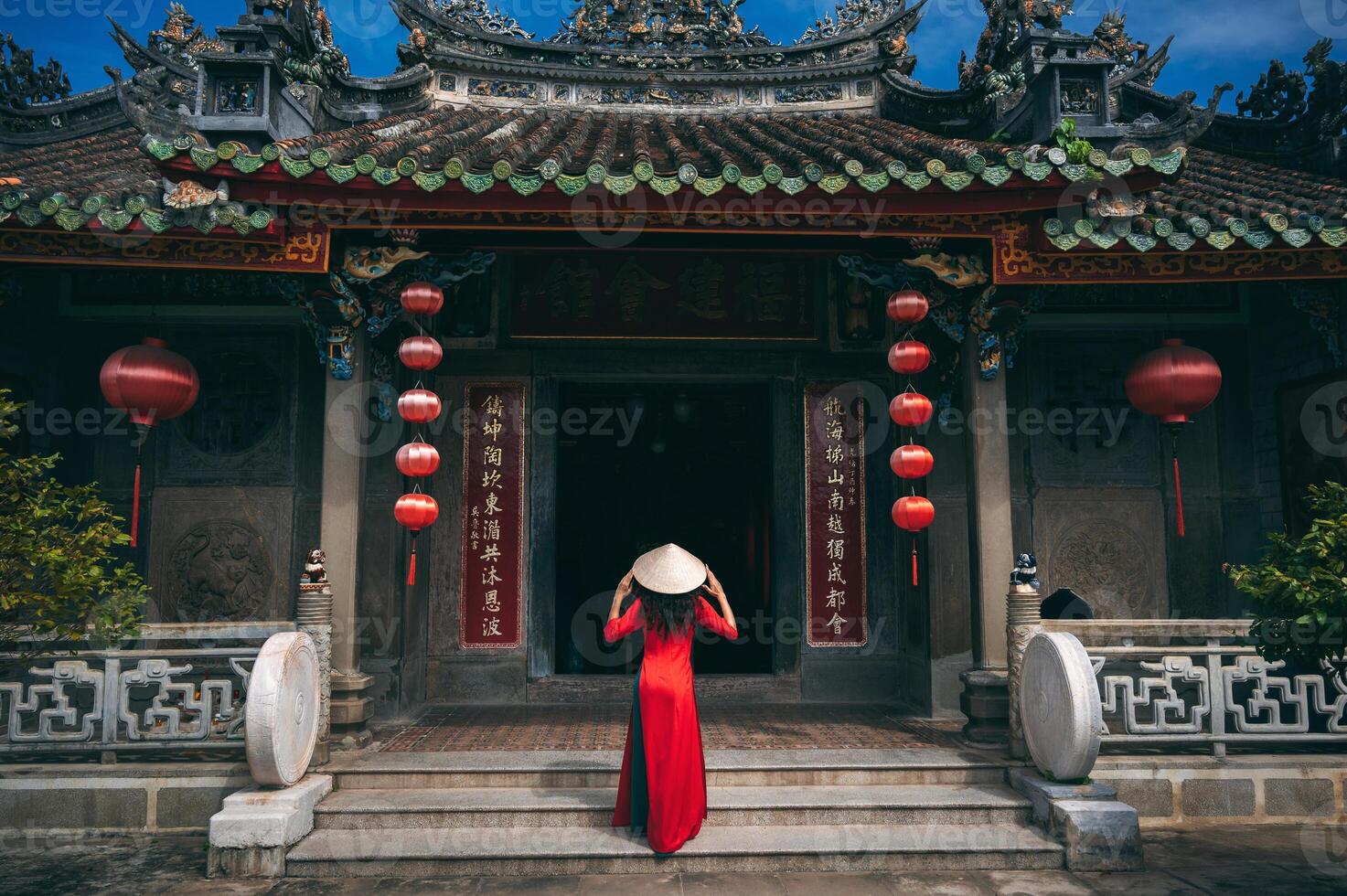A woman in a traditional Vietnamese costume and a conical hat on the background of an ancient building in Hoi An, Vietnam. photo