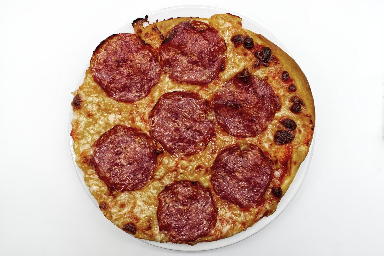 Delicious pepperoni pizza with golden crust and melted cheese on a white plate isolated photo