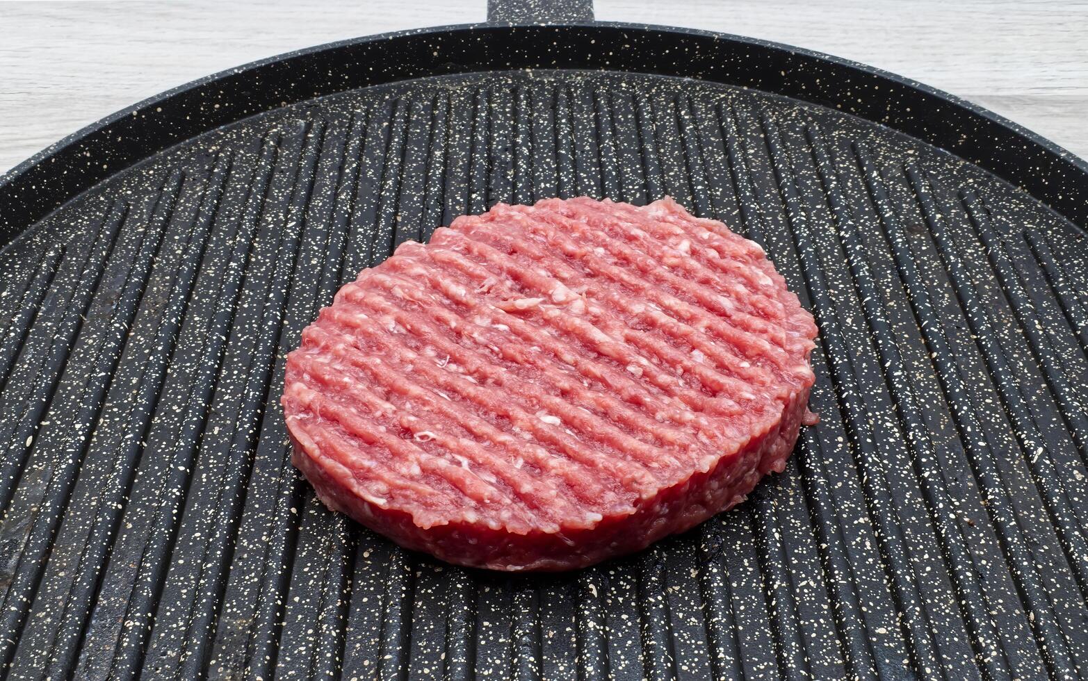 Raw hamburger patty on a griddle, ready to cook. photo