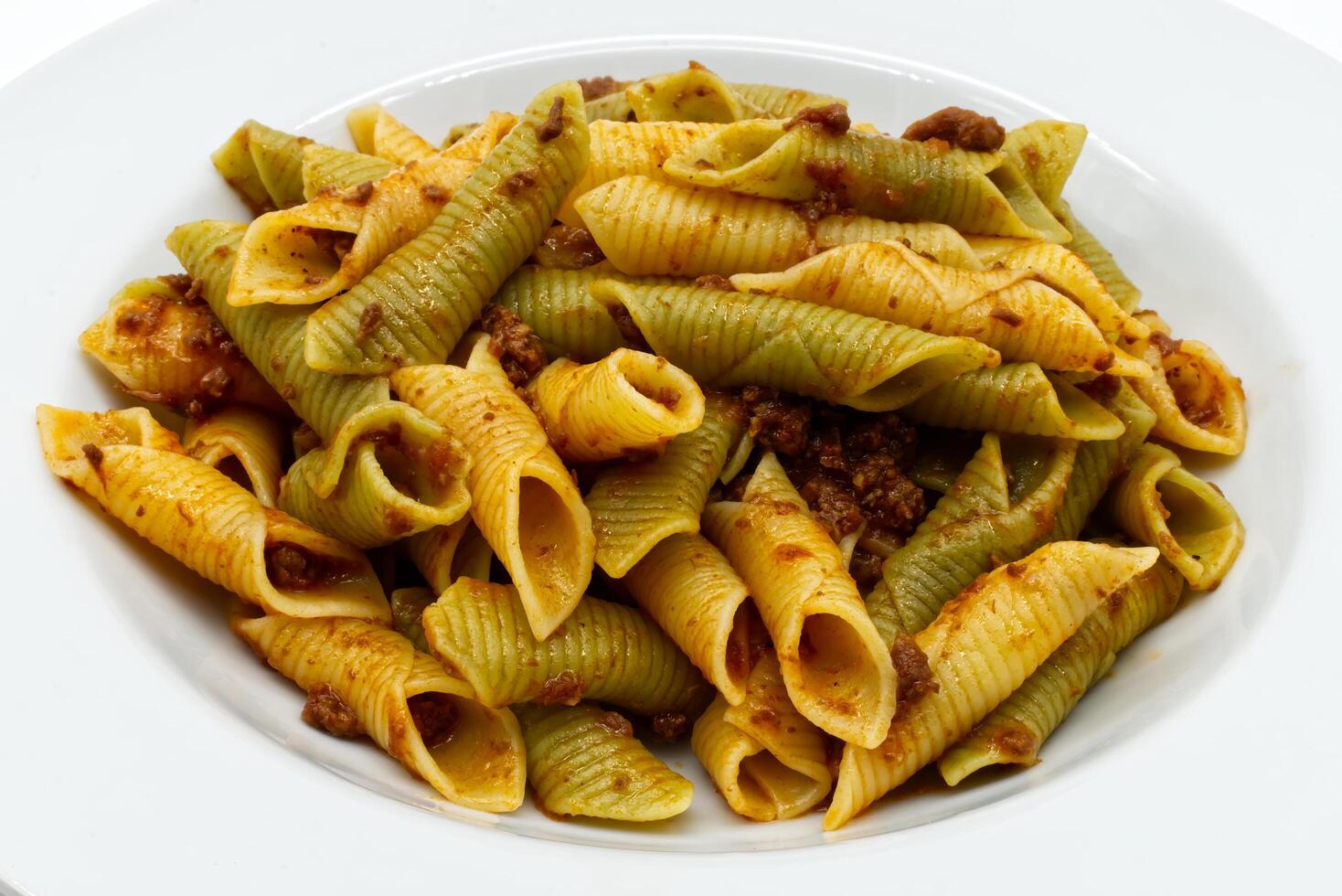 Classic italian spinach and regular shell pasta with savory bolognese meat sauce served on white plate photo