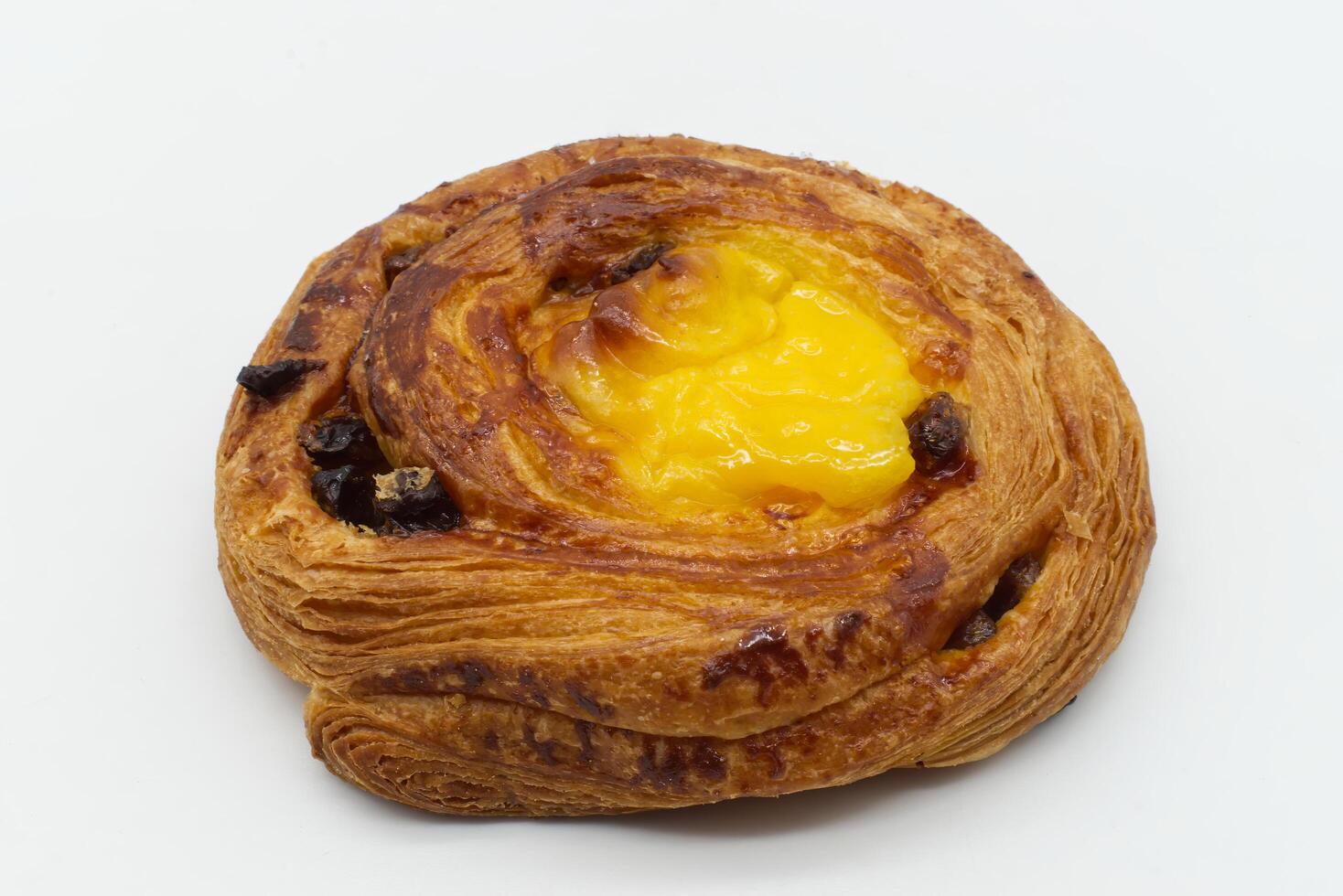 A single spiral-shaped sweet roll with raisins and custard filling ready to eat for breakfast or snack time photo