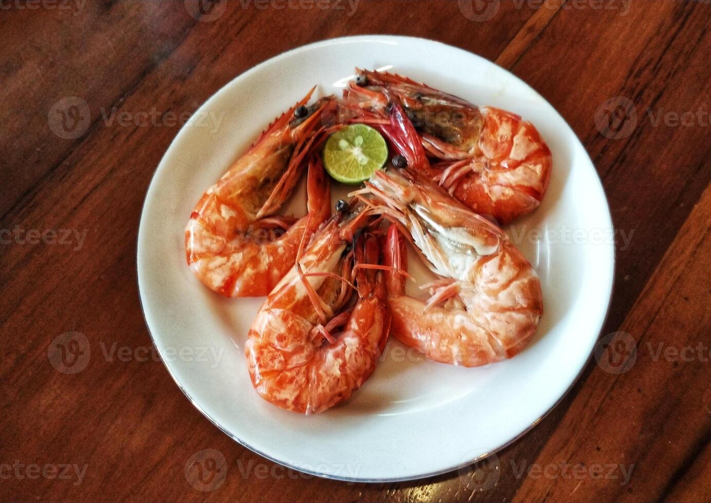 A plate of shrimp with a lime wedge on top photo