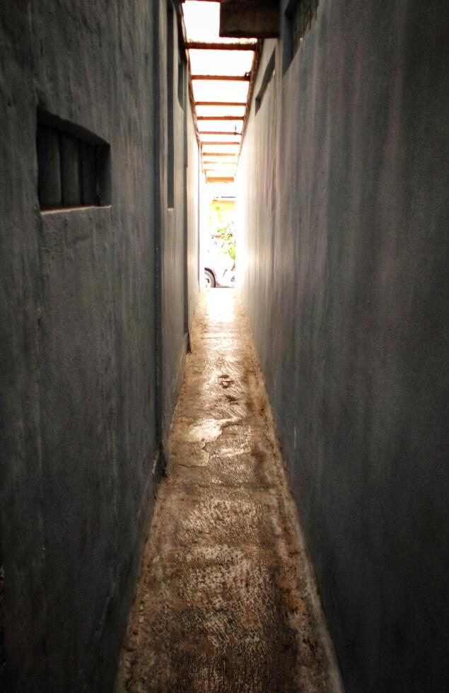 A narrow alleyway with a blue wall and a car parked in the distance photo