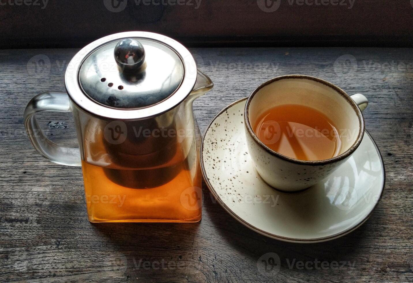 A cup of tea and a teapot on a wooden table photo