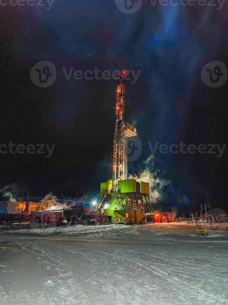 illuminated oil drilling rig working at night in snowy environment. Mining. Mobile photo