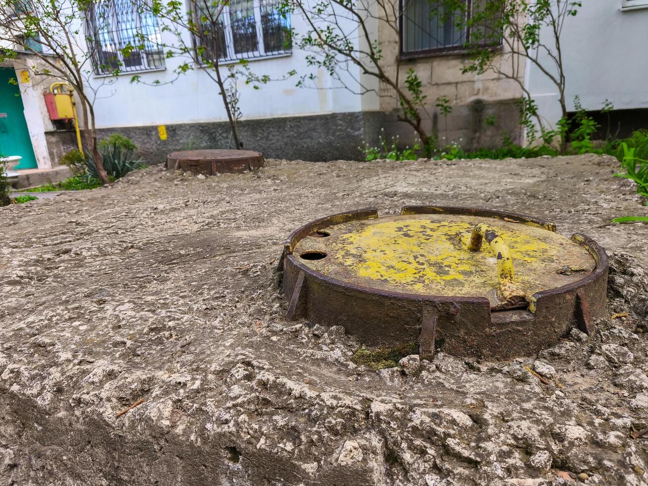 A rusty metal pipe is sitting on the ground in front of a house. The pipe is yellow and has a hole in it. The scene is somewhat eerie and gives off a feeling of decay and neglect photo