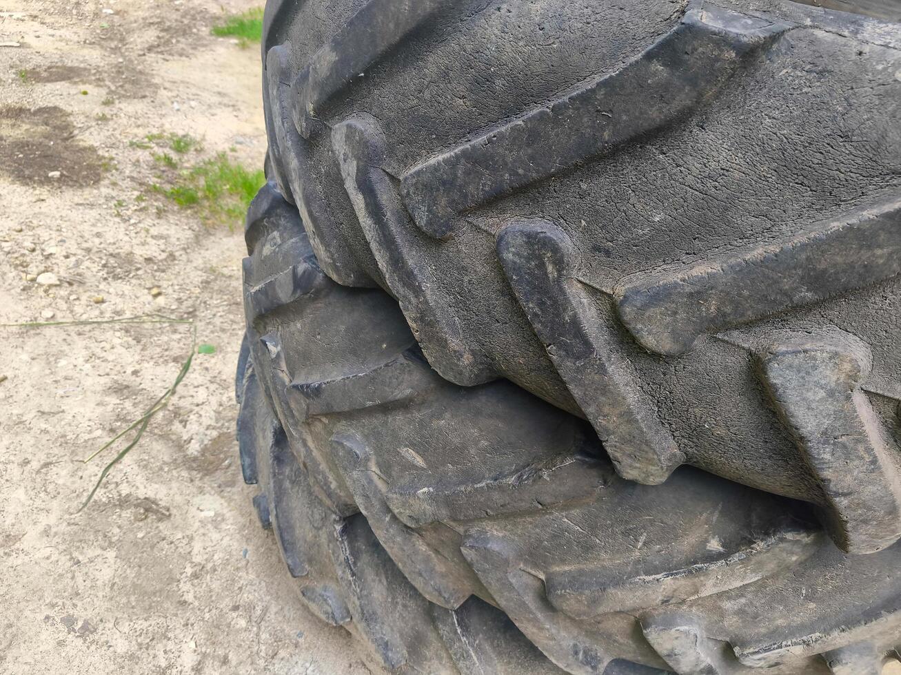 The tire is old and worn, with a lot of dirt and grime on it. It's a tire on a tractor, and it's not in good condition photo