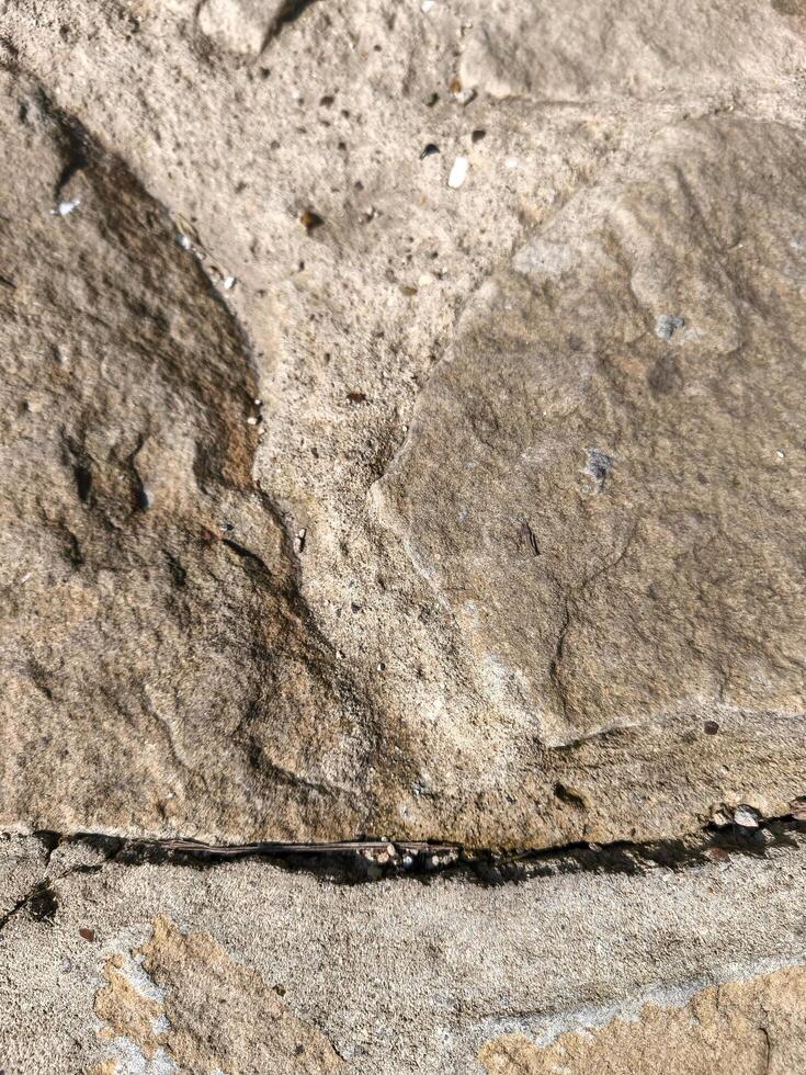 A rock with a crack in it. The crack is visible and the rock is grey. The crack is long and narrow photo