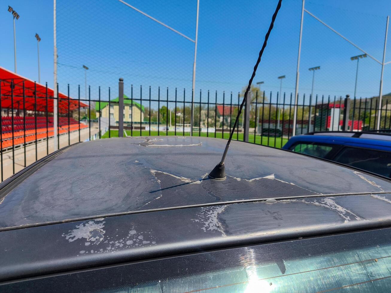 A car with a black roof has a small antenna on top. The antenna is black and is pointing to the right photo