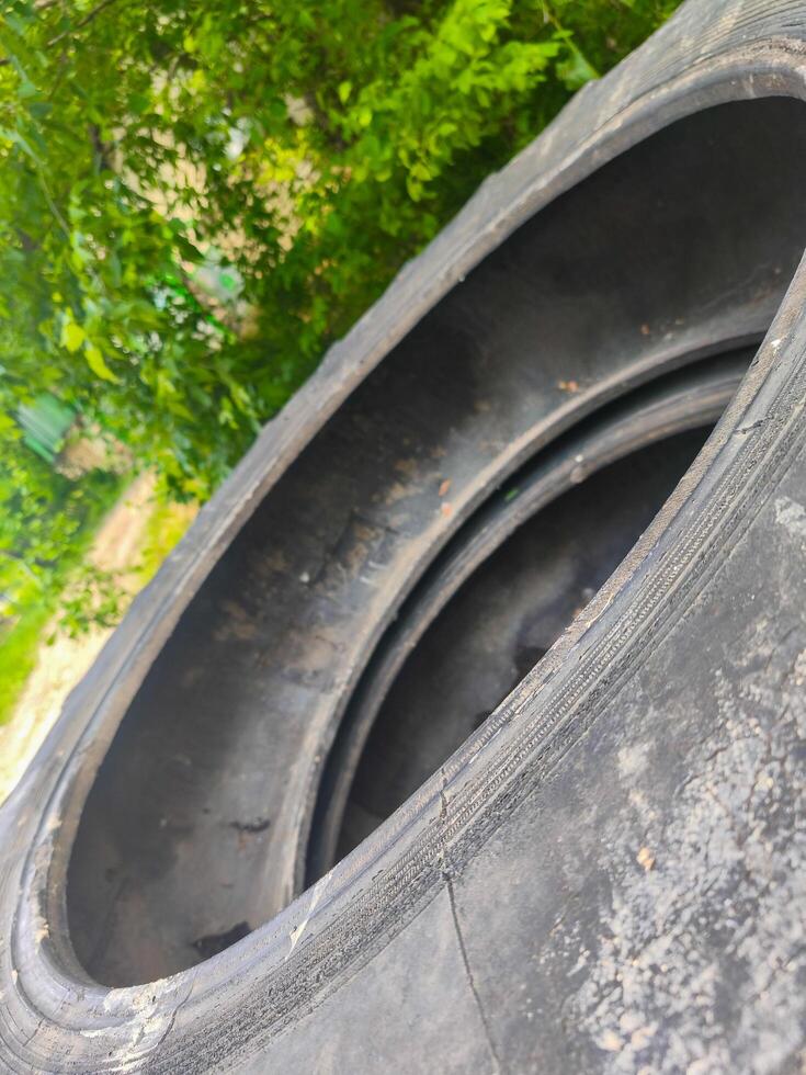 A tire with a hole in it is shown in a forest. The tire is black and has a hole in the middle. The tire is surrounded by trees and bushes, giving the image a natural and peaceful feel photo
