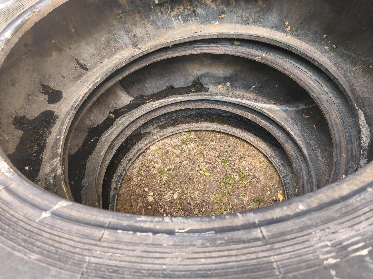 A tire is in a hole in the ground. The tire is black and has a hole in it photo