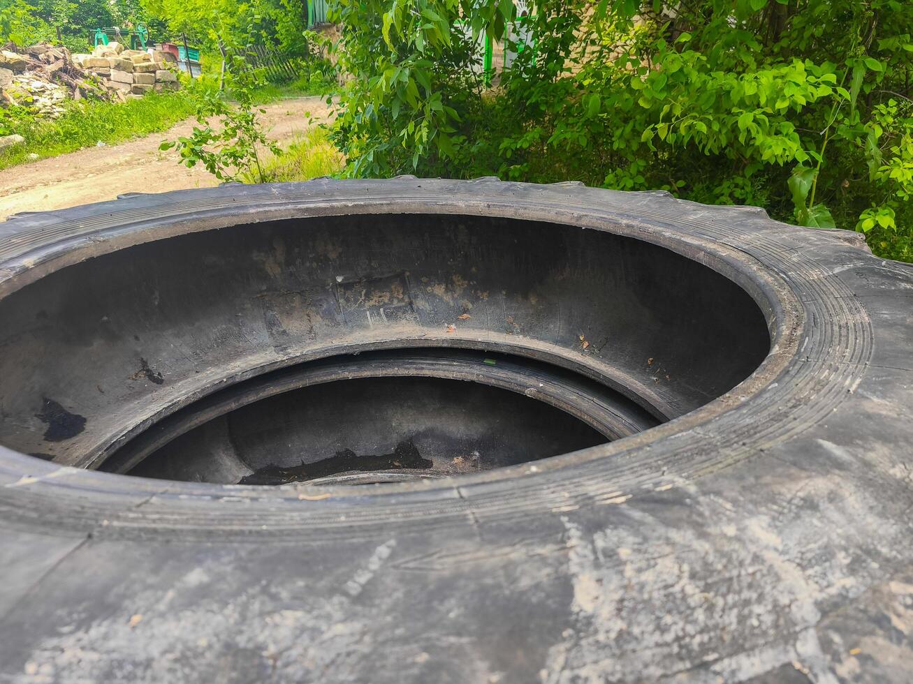 A tire is sitting in a hole in the ground. The tire is black and has a hole in it photo
