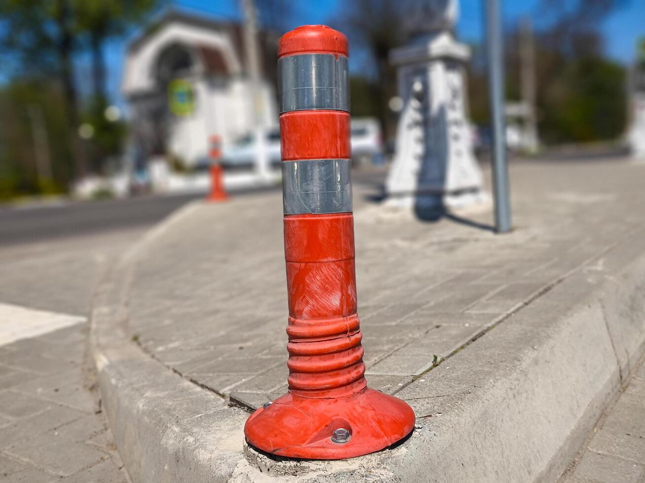 A red and white traffic sign is on the sidewalk. The sign is on a corner of a street photo