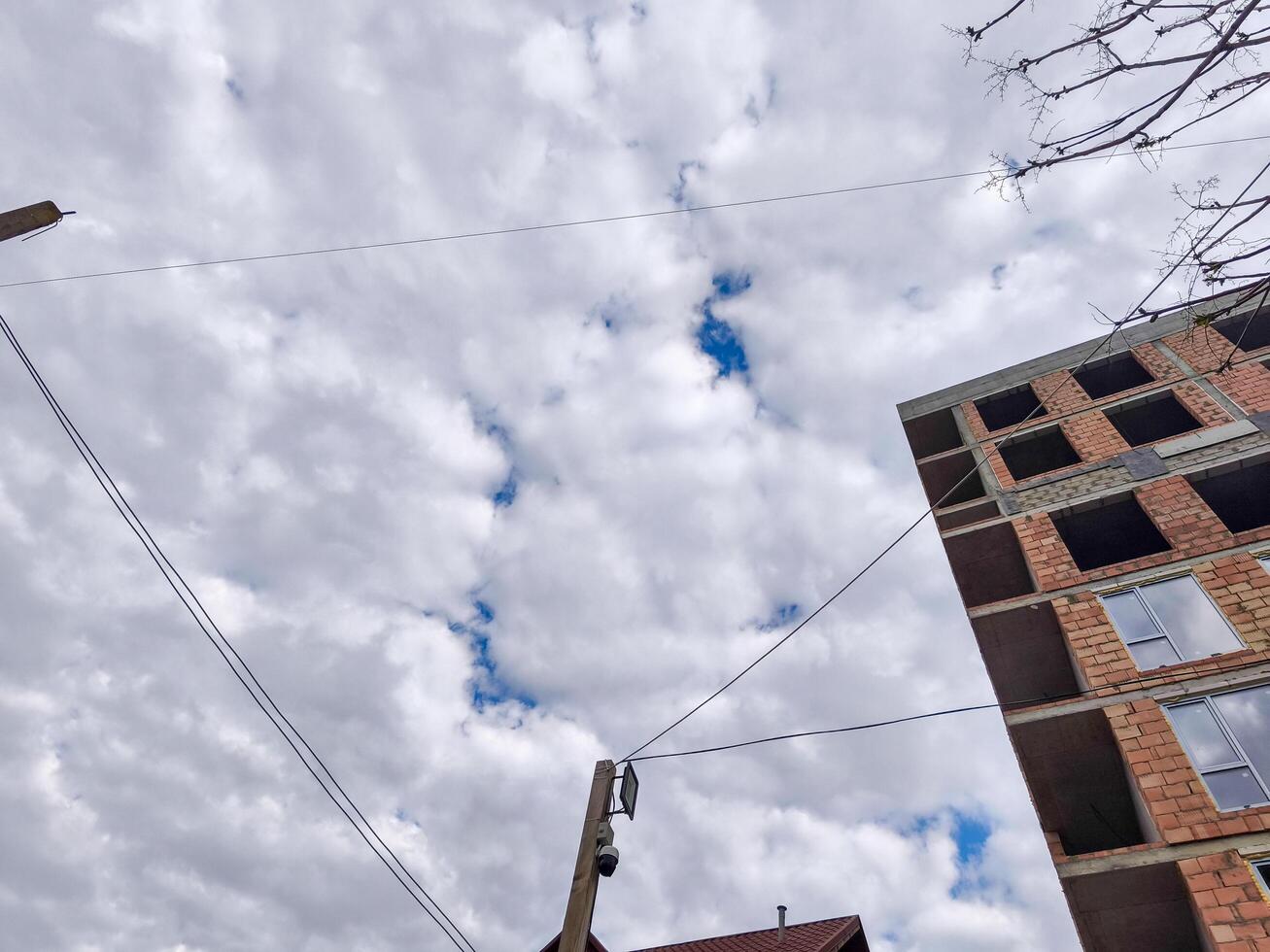 A building with a lot of wires and a cloudy sky in the background. The sky is blue and the clouds are white photo