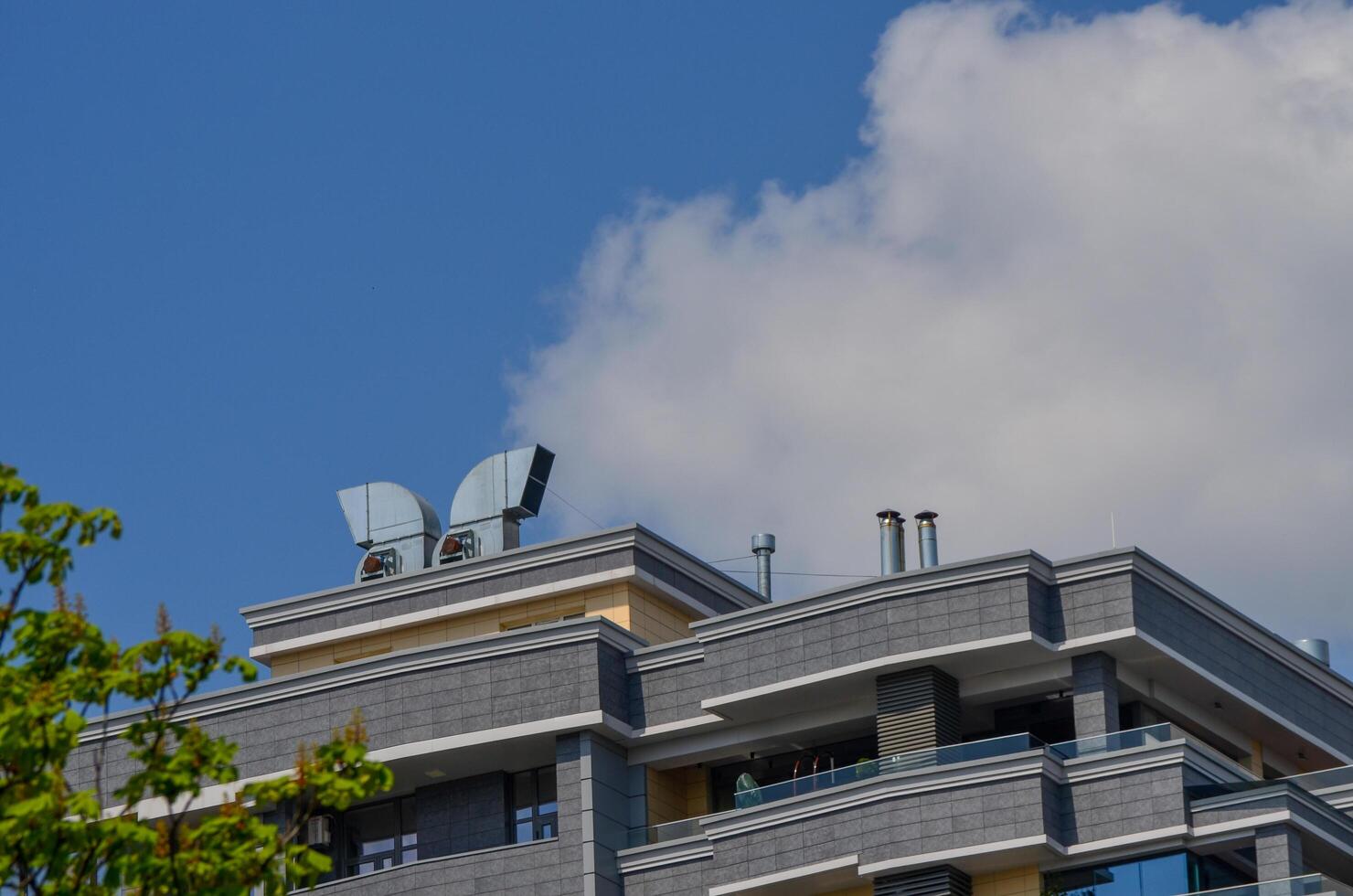 A tall building with a blue sky in the background. The building has a lot of vents on the roof photo