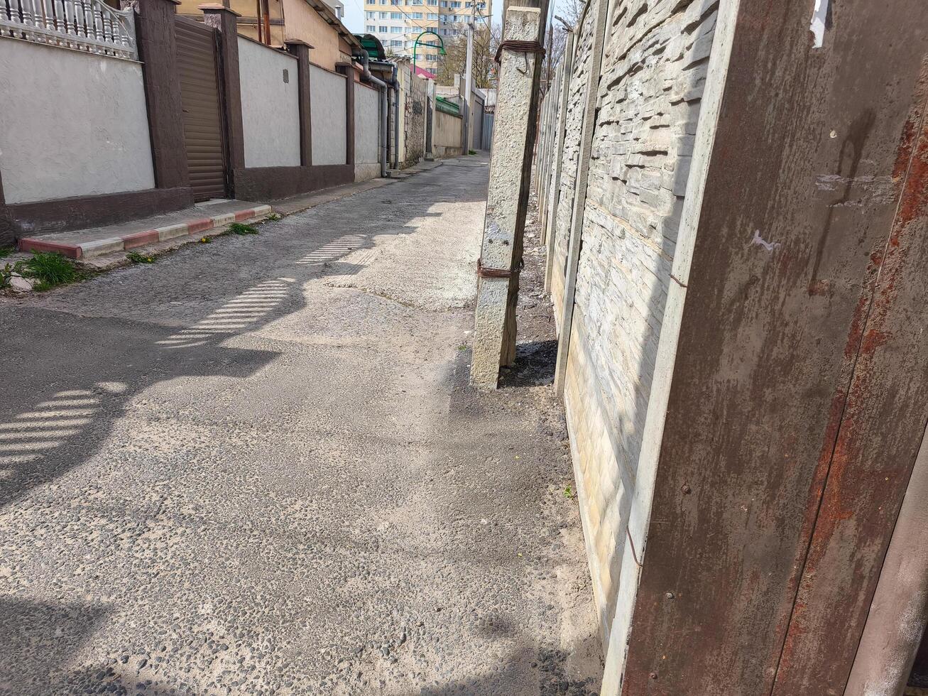 A street with a brick wall on the side. The wall is brown and has a few cracks photo