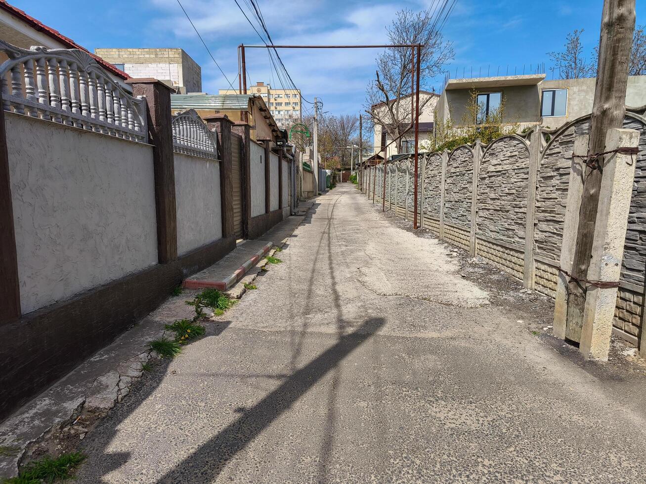 A street with a fence on both sides and a pole in the middle. The pole is holding a metal bar photo