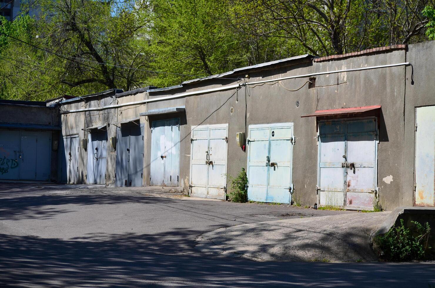 A row of old blue doors sit in front of a building. The building is old and has a rustic appearance. The doors are open and the building is empty photo