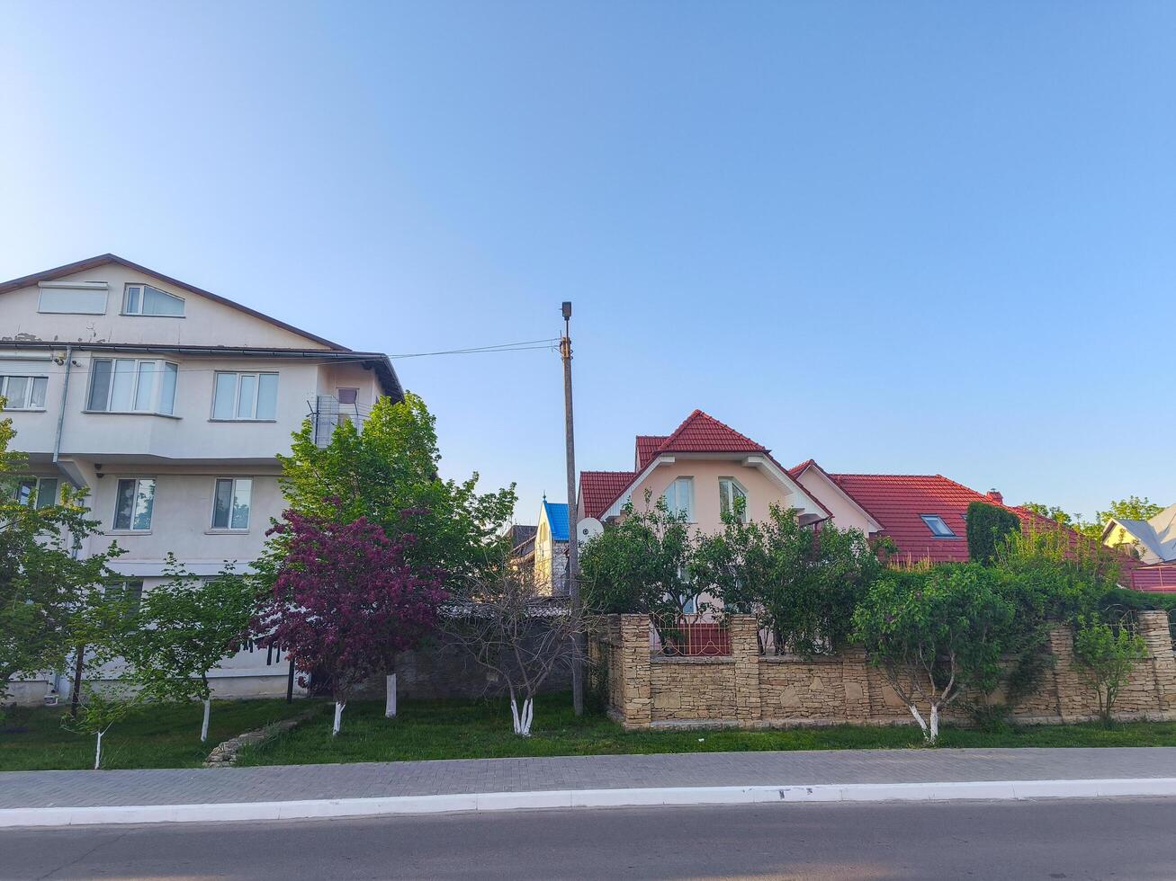 A street with a house on the left and another house on the right. The houses are white and red photo