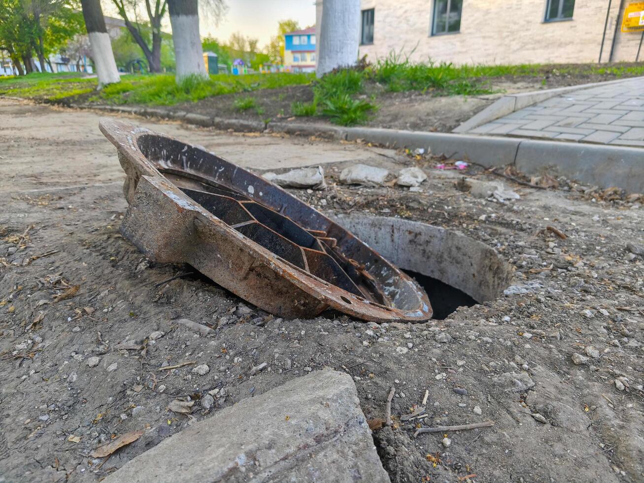 A damaged pipe is sitting in a hole in the ground. The pipe is broken and has been discarded, likely due to its age or damage. The hole in the ground is filled with dirt and debris photo