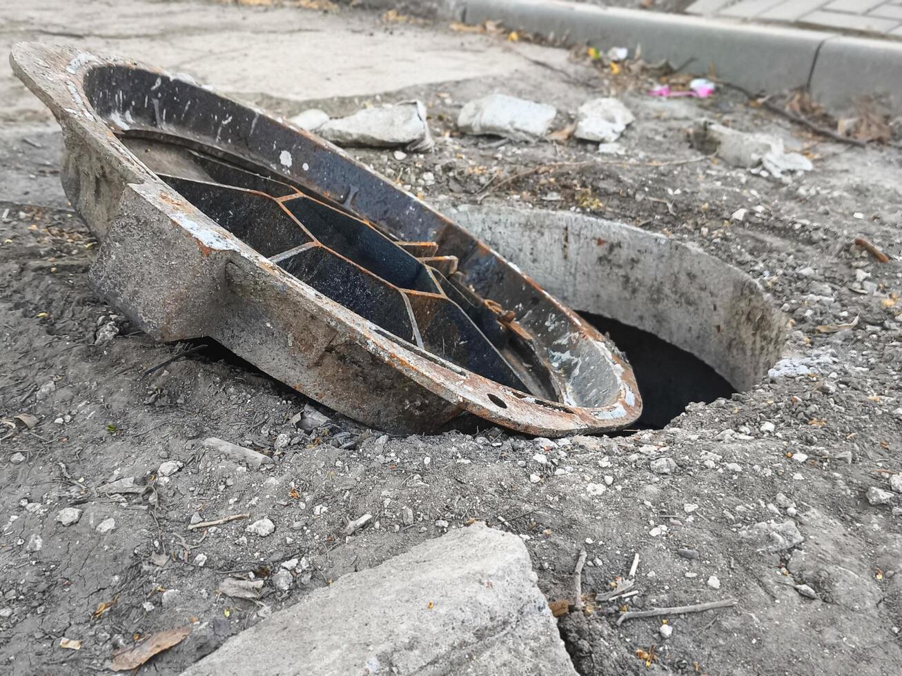 A broken pipe is in the ground with a hole in it. The hole is filled with water photo