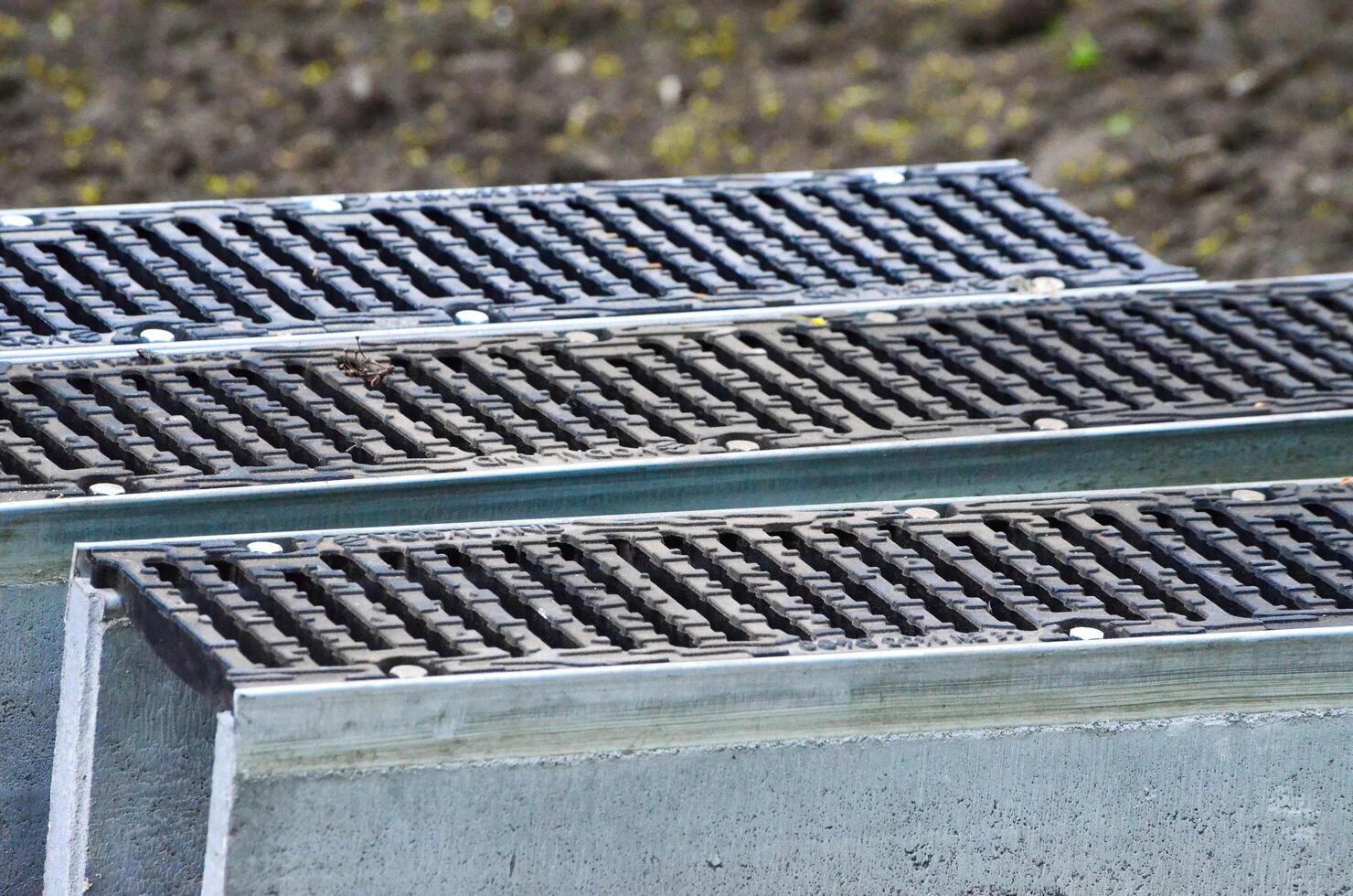 A row of metal grates are stacked on top of each other. The grates are black and silver, and they are arranged in a neat row. Concept of order and organization photo