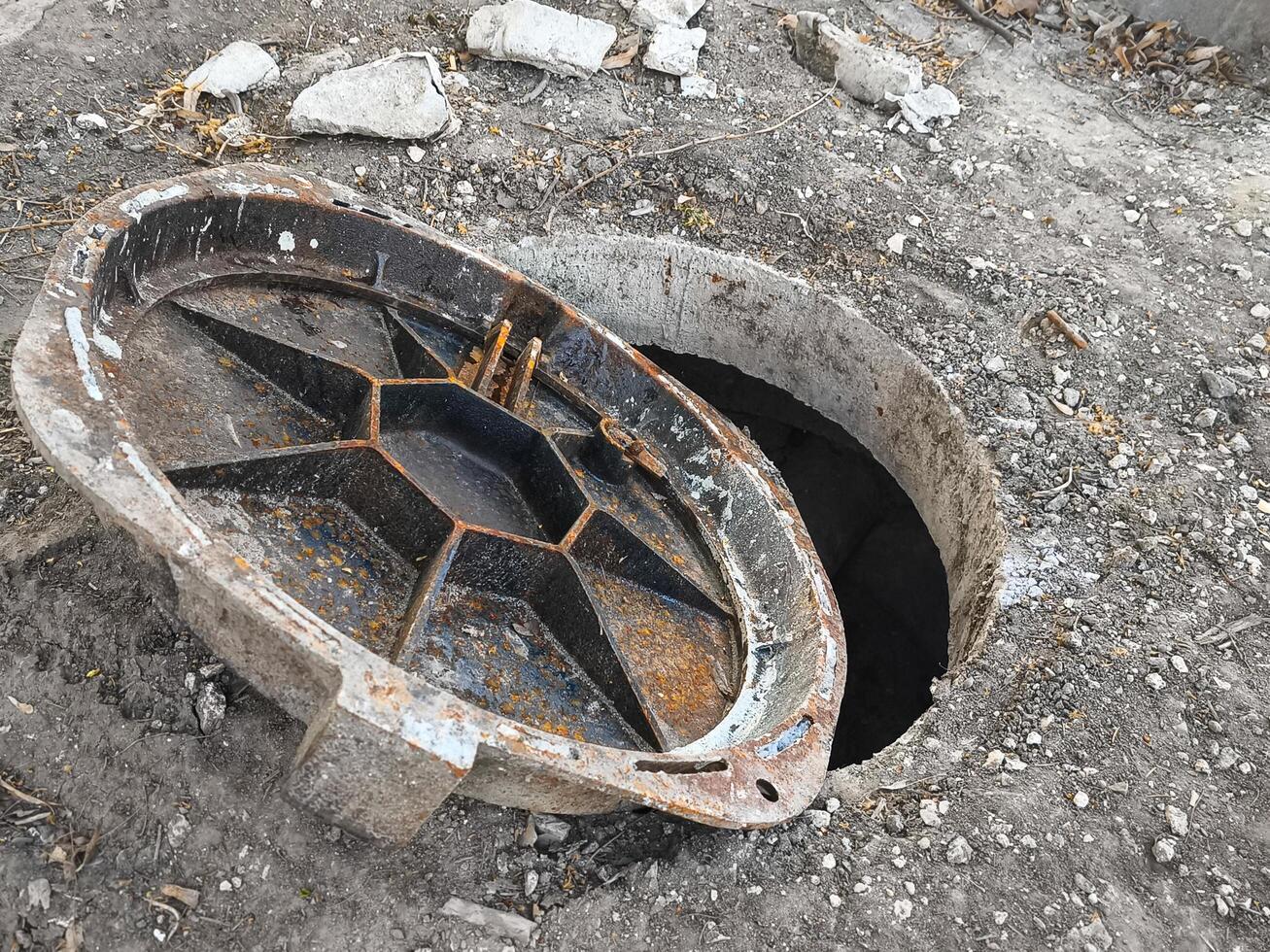 A rusty metal pipe is sitting in the ground with a hole in it. The hole is open and the pipe is missing photo