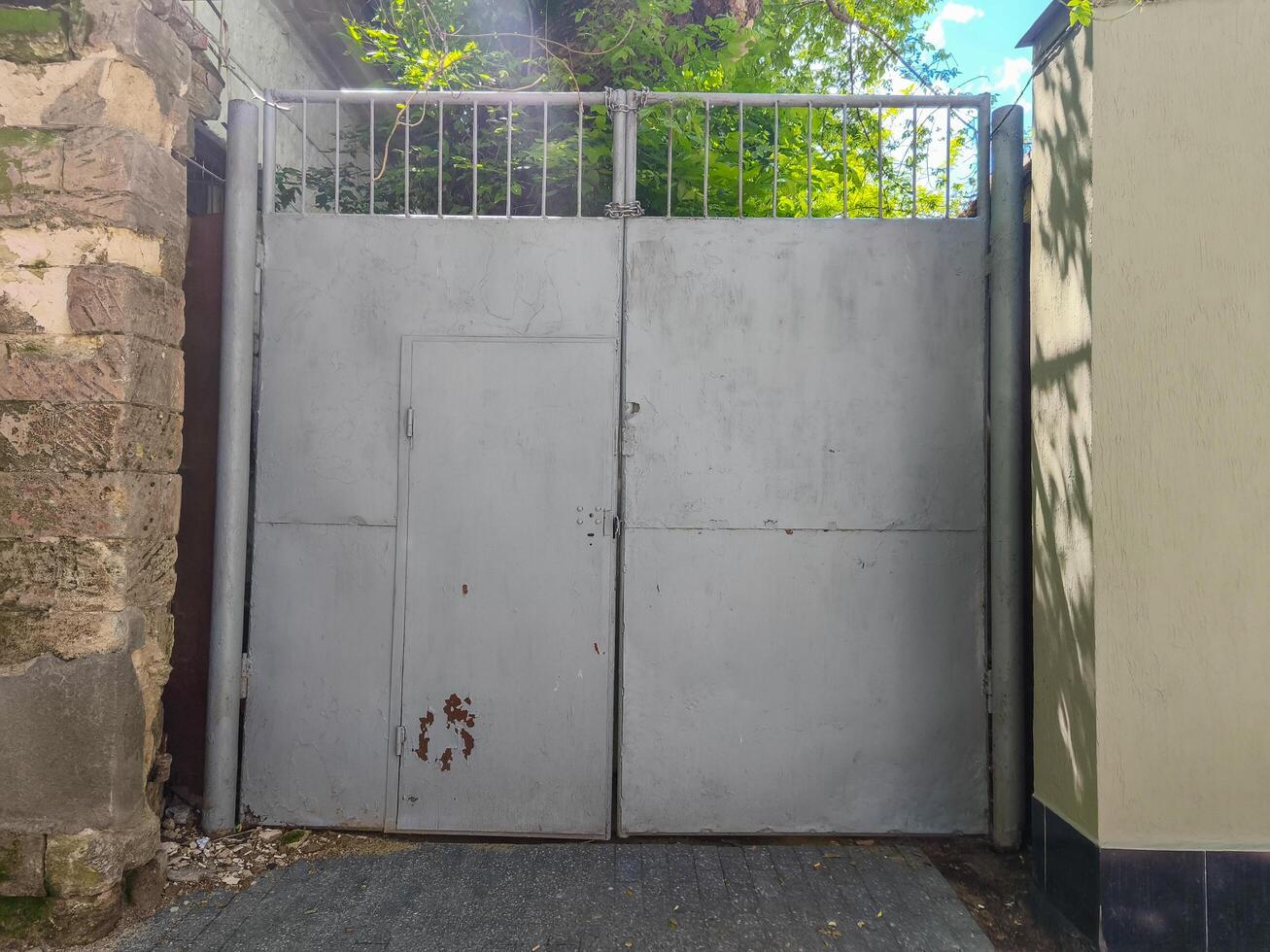 The gray colored gate is closed. The gate is made of metal and is located in front of the building photo