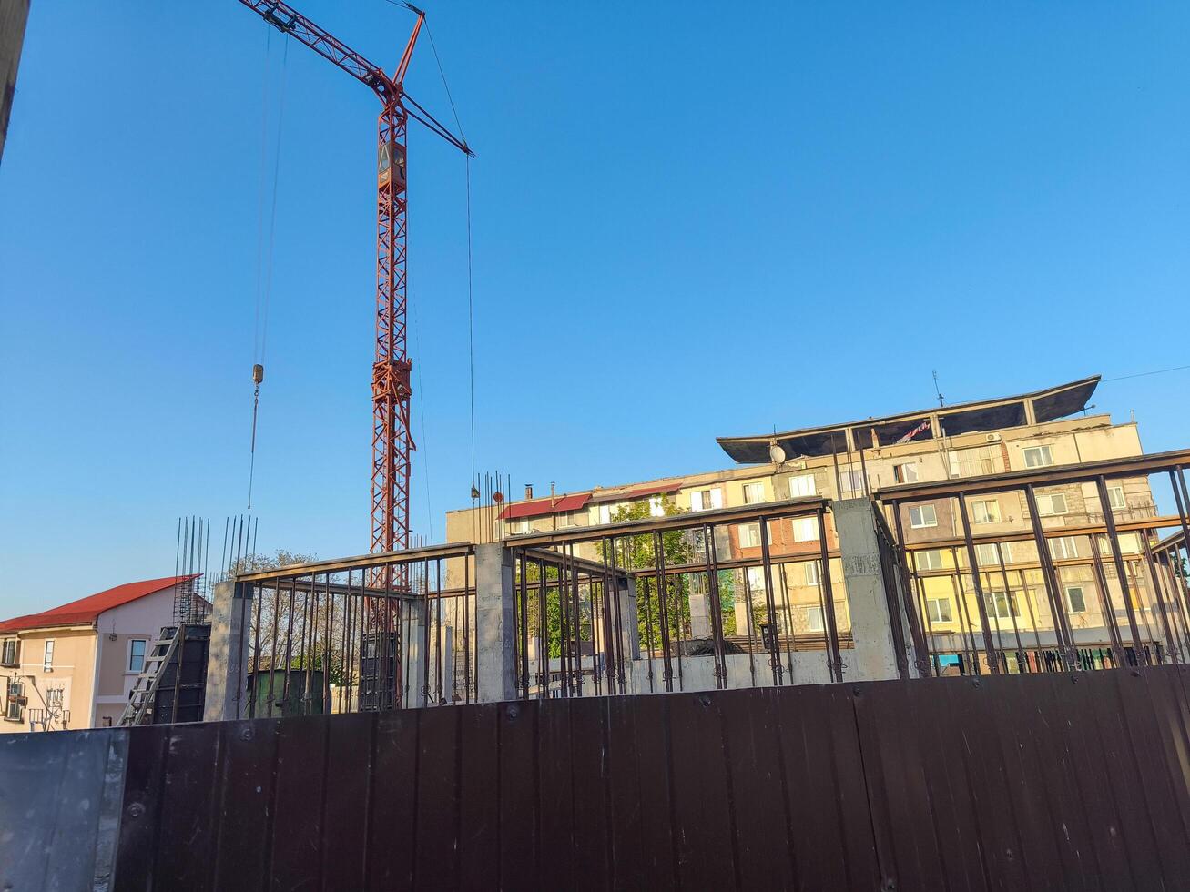 A crane is lifting a large object in front of a building. The sky is clear and blue photo