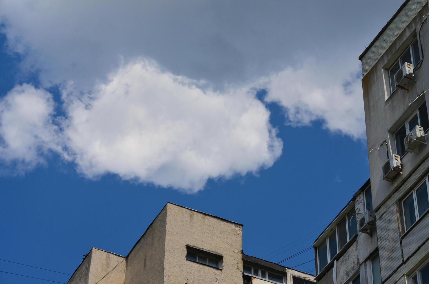 A large cloud is in the sky above a building. The sky is blue and the cloud is white photo