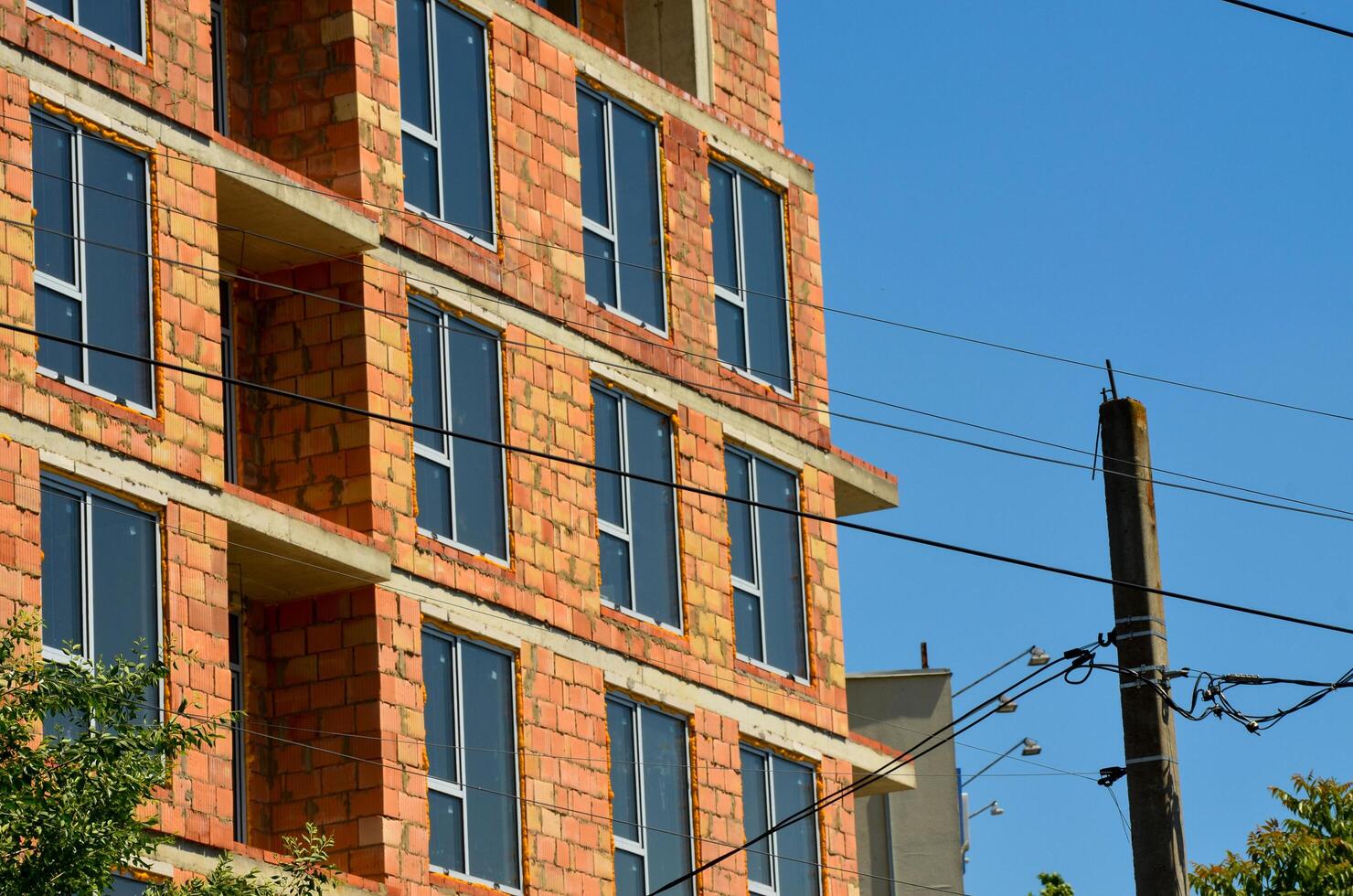 A tall brick building with many windows and a power line running above it. The building is under construction photo