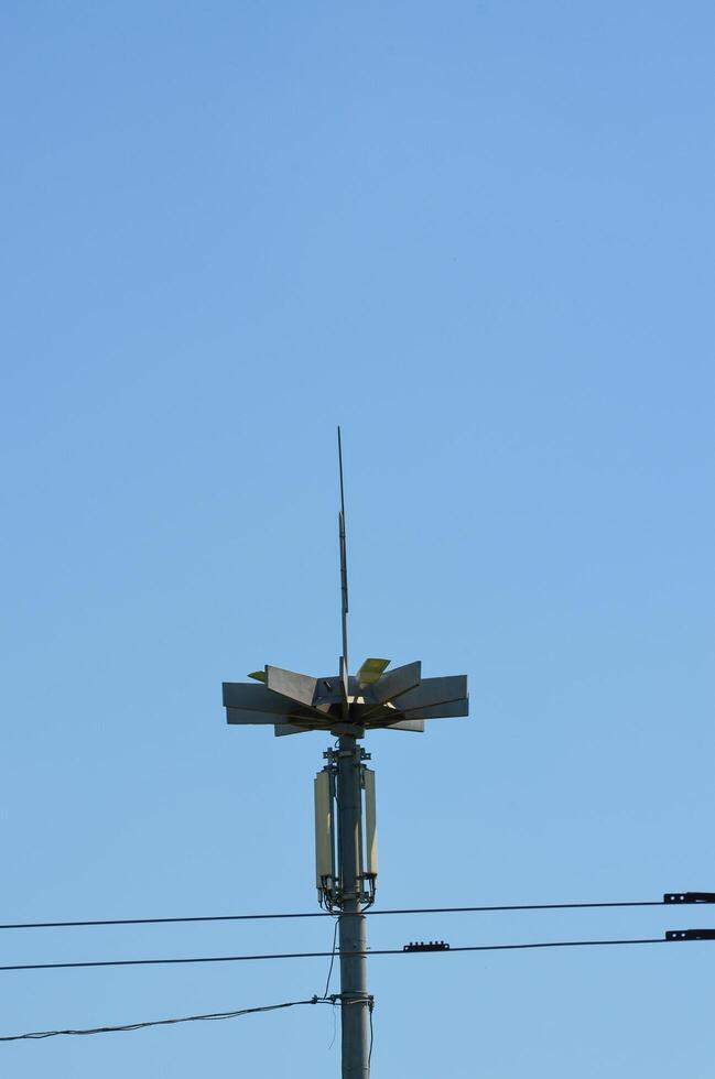 A tall pole with a light on top of it. The pole is surrounded by wires and the sky is clear photo