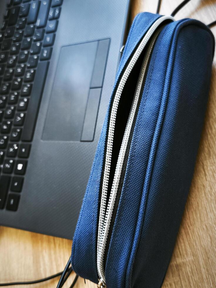 A laptop is open to a blue case with a zipper. The laptop is on a wooden table photo