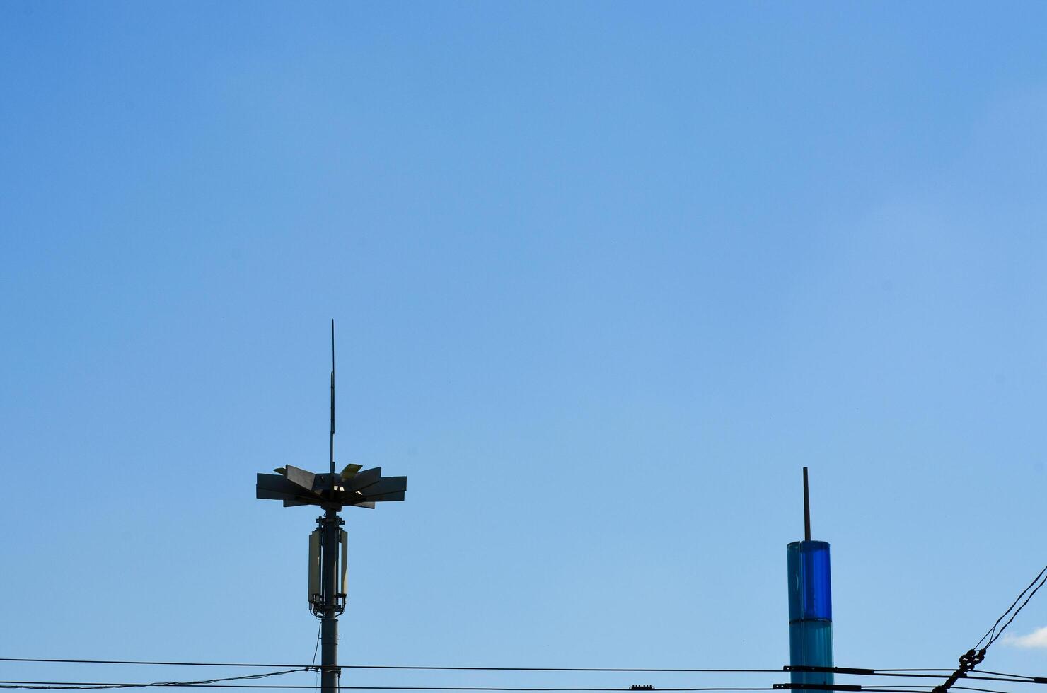 A tall pole with a light on top is next to a blue building. The sky is clear and blue photo