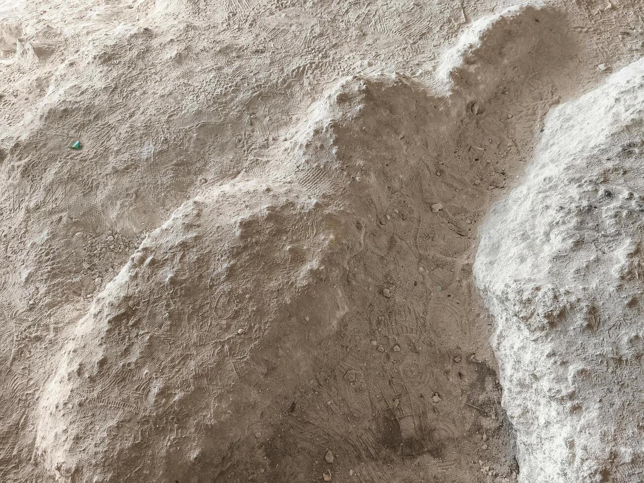 A pile of sand with a small object in the middle. The sand is brown and the object is green photo