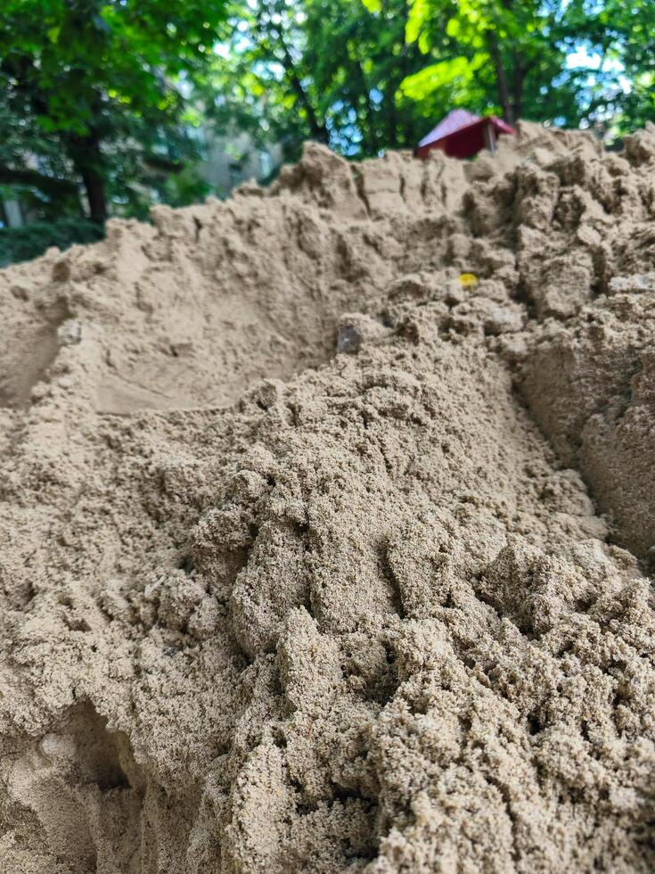 A mound of sand with a red tent in the distance. The sand is a light brown color and the tent is a bright red photo
