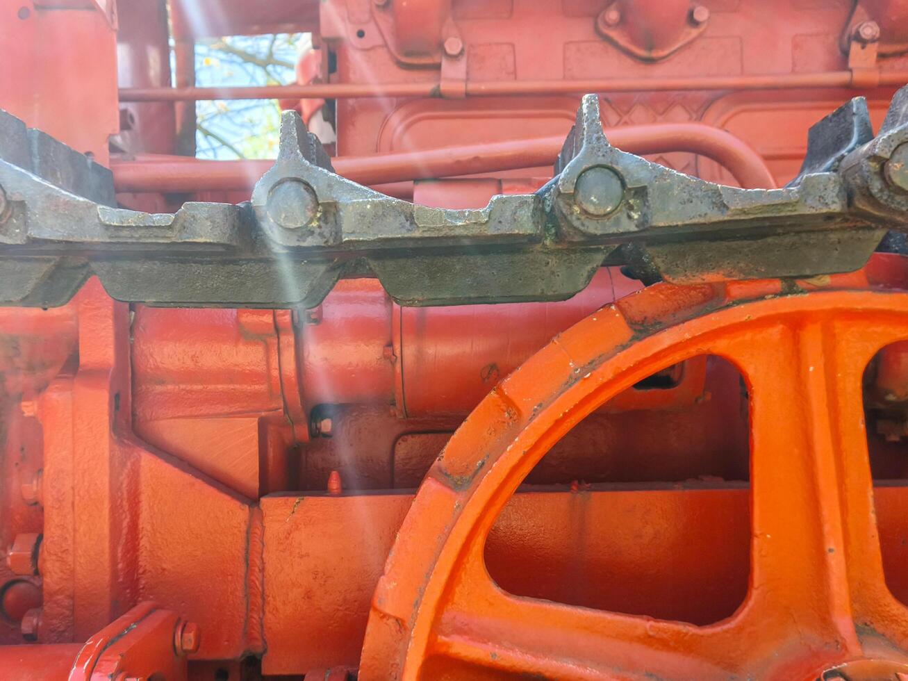 The front of a red tractor with a black wheel. The wheel is orange and has a black rim photo
